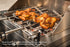 Two whole chickens roasting over charcoal on Tucker R Class Cypriot skewers with Tucker Long Prong