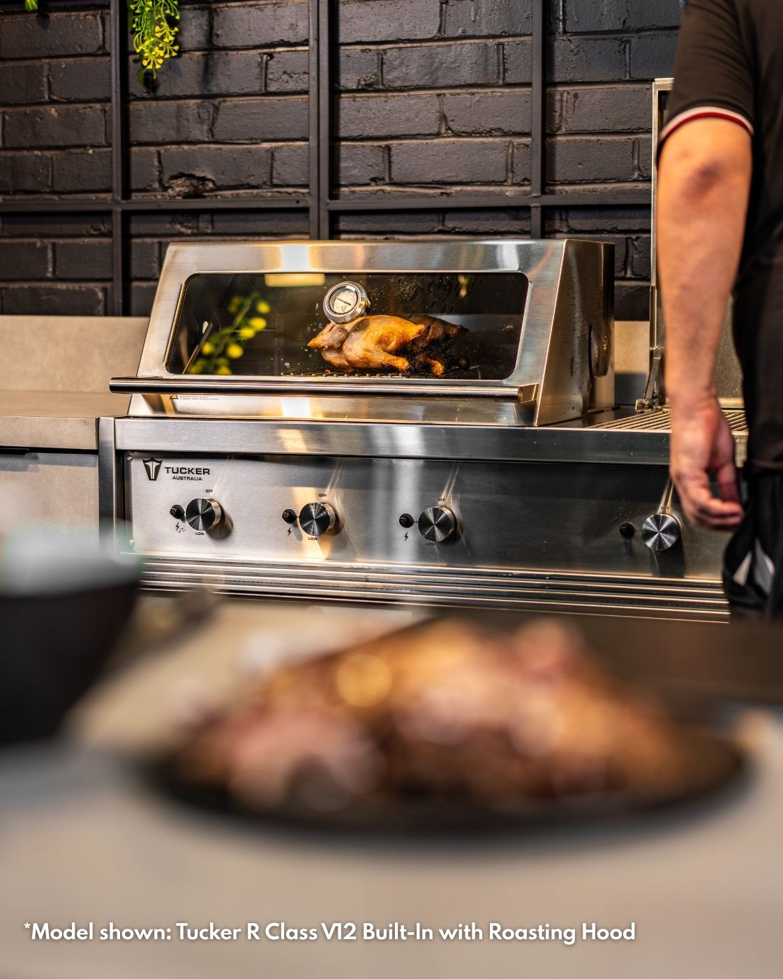 Whole roast chicken visible through the glass roasting hood of a Tucker R Class built-in BBQ